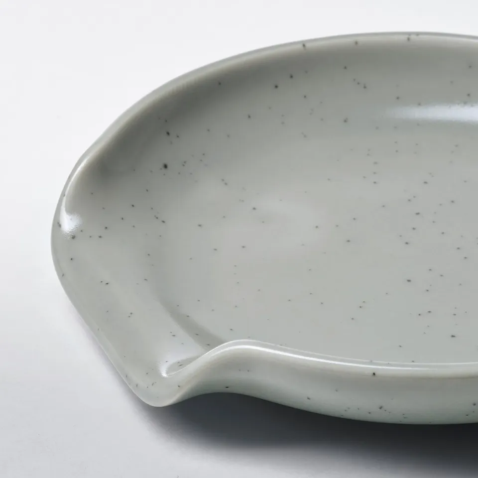 Grey speckled spoon rest on white.