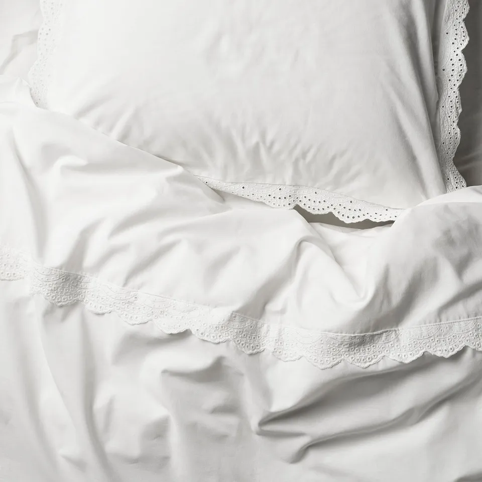 White duvet cover set with intricate lace trims, made of soft, breathable cotton.