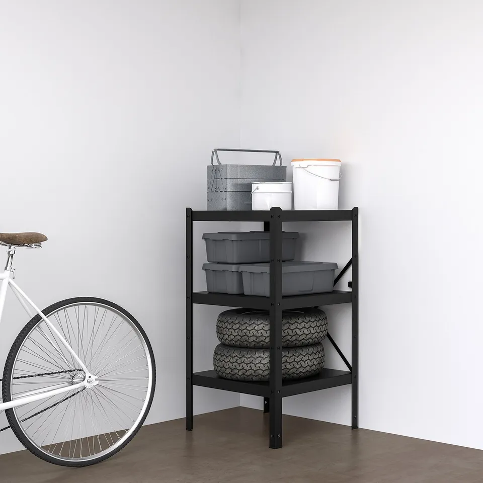 BROR black shelf in room corner with containers, bucket, tyres, and partial bicycle.