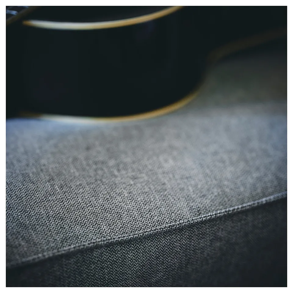 Close-up of KIVIK sofas dark grey, textured fabric, showcasing its herringbone pattern and clean stitching.