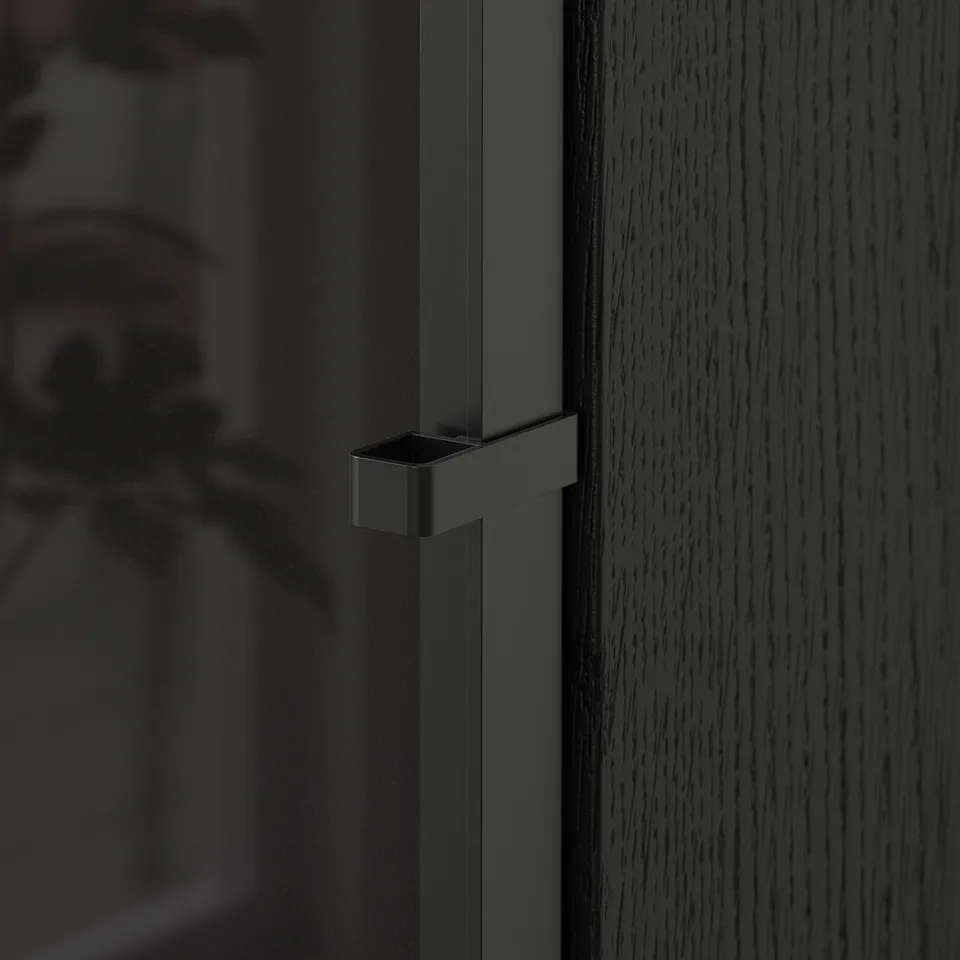 Close-up of a sleek, dark handle on a smooth, modern cabinet door.