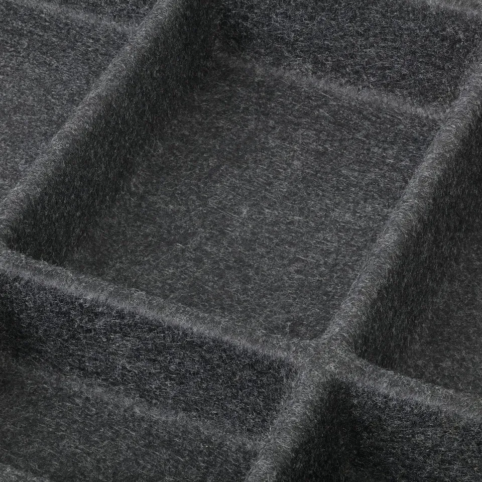 Close-up of textured, dark fabric with thick folds and shadows, highlighting its soft quality and intricate details.