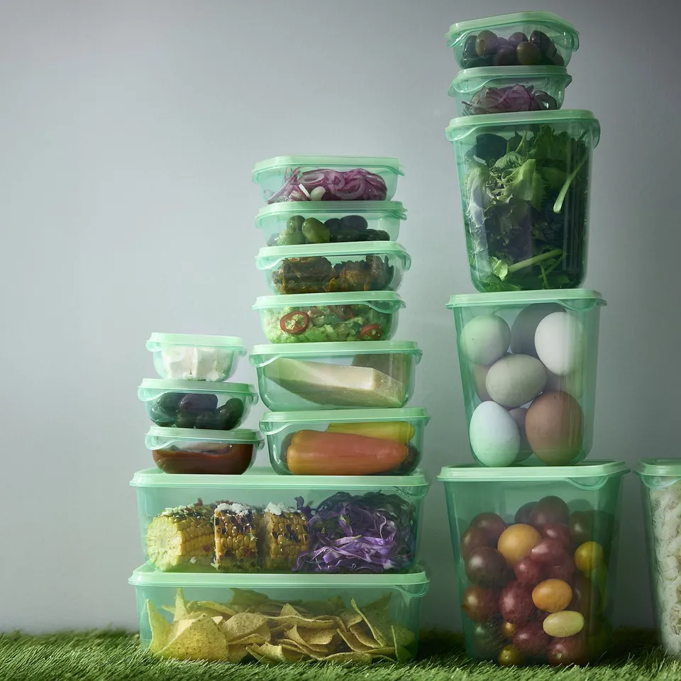 Green plastic food containers in various sizes, neatly stacked with different snacks.