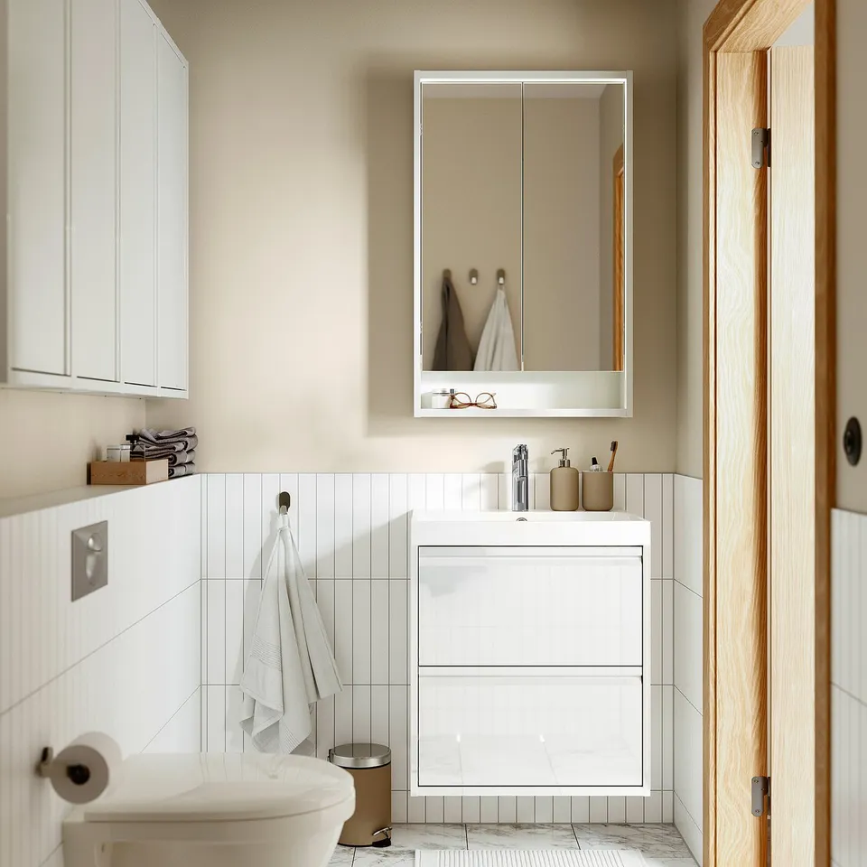 Modern white bathroom with glossy ÄNGSJÖN vanity, sleek sink, mirror, toilet, and wooden door.