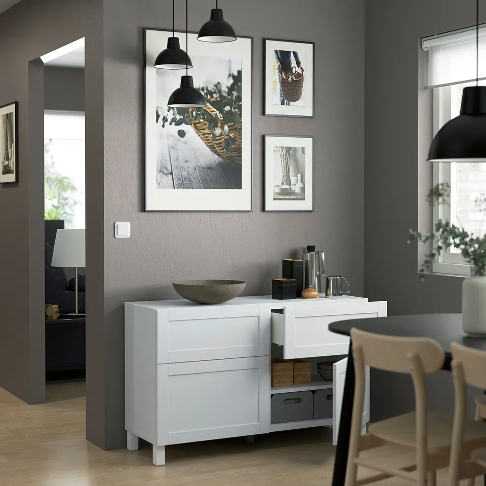 Modern living room with white BESTÅ sideboard, featuring adjustable shelves, soft-closing drawers, and wall art.