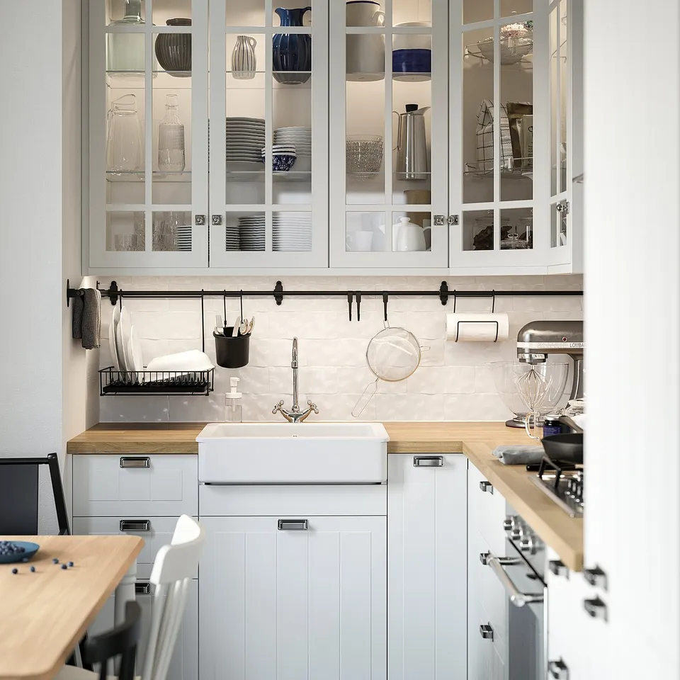 Modern kitchen with white METOD cabinets, glass doors, wooden countertop, farmhouse sink, and stainless steel appliances.