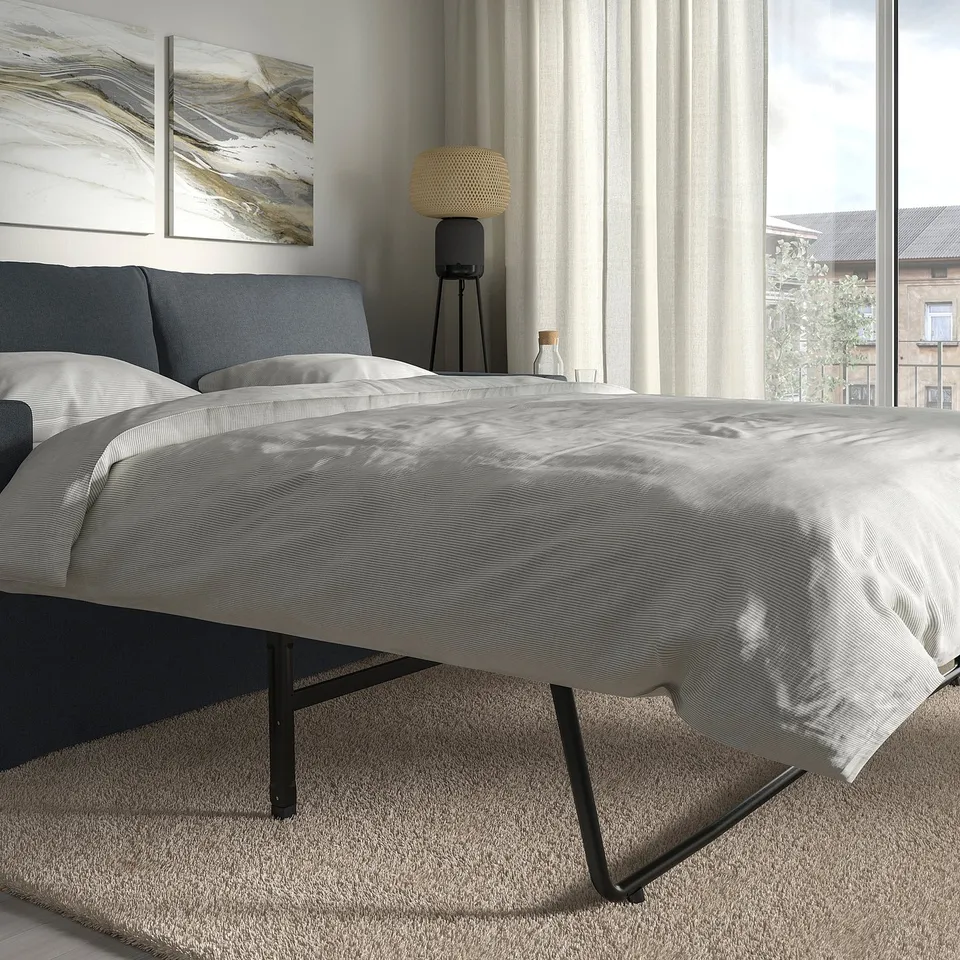 Modern bedroom with HYLTARP sofa-bed, reversible cushions, large window, sheer curtains.