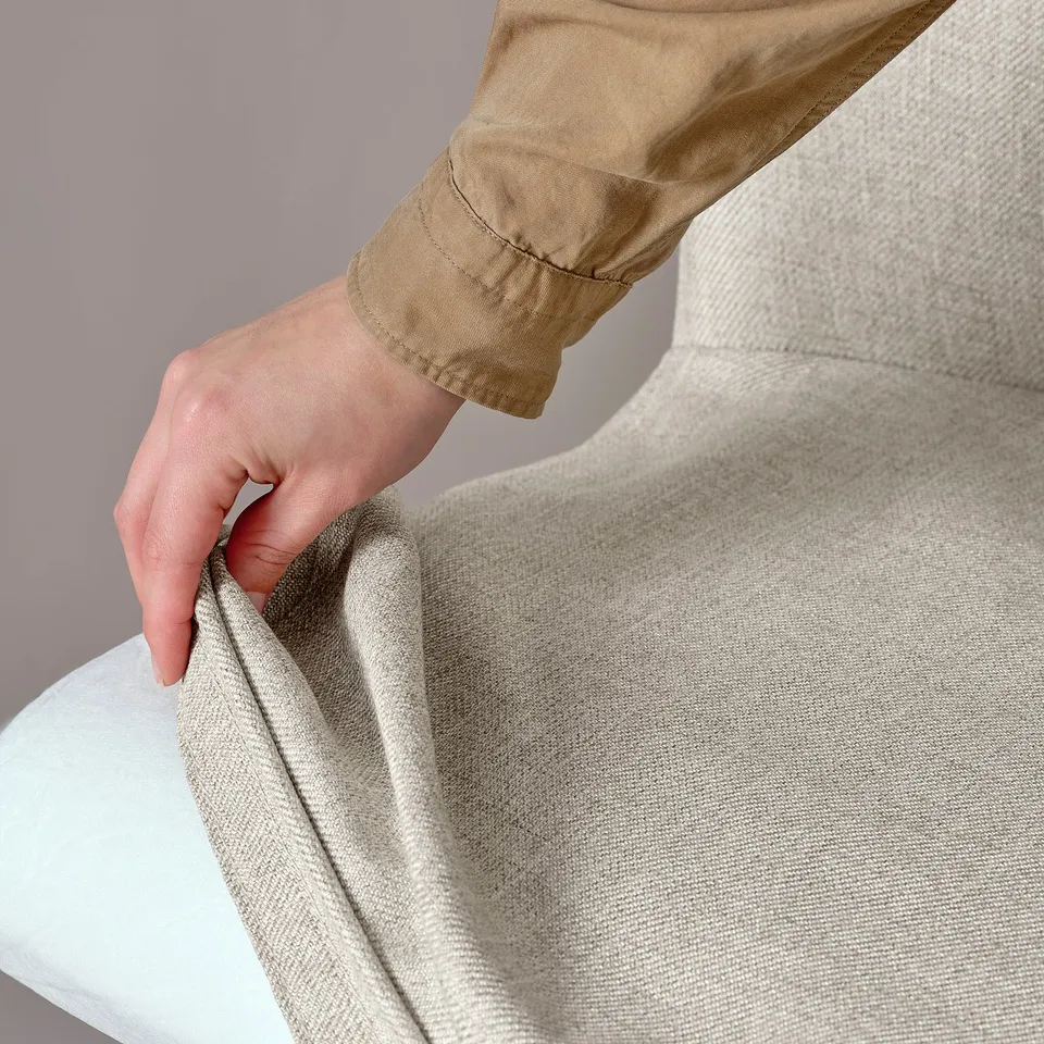 Person adjusting soft, beige swivel chair, showcasing its comfort and ease of use.