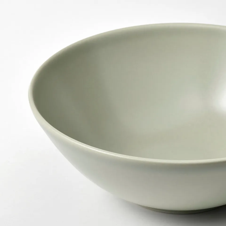 Green glossy bowl on white surface.
