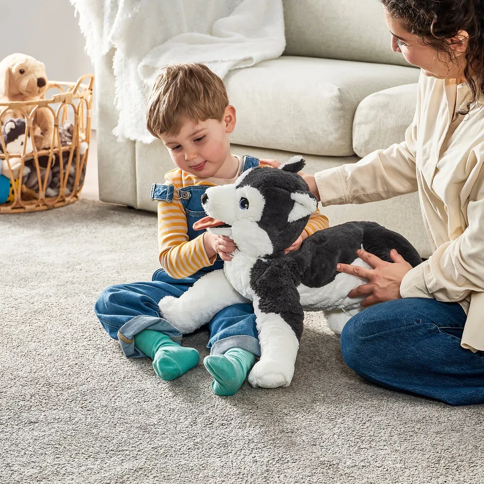 Child plays with stuffed animal on rug in living room.