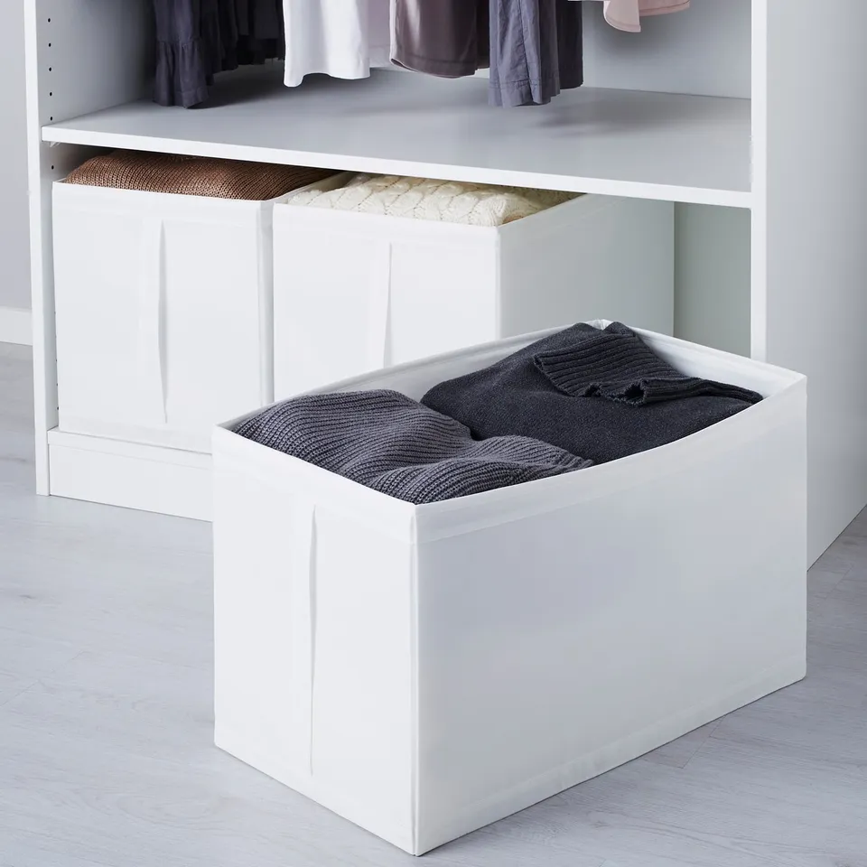 White storage boxes in wardrobe, holding folded clothes and blankets, with handles for easy access.