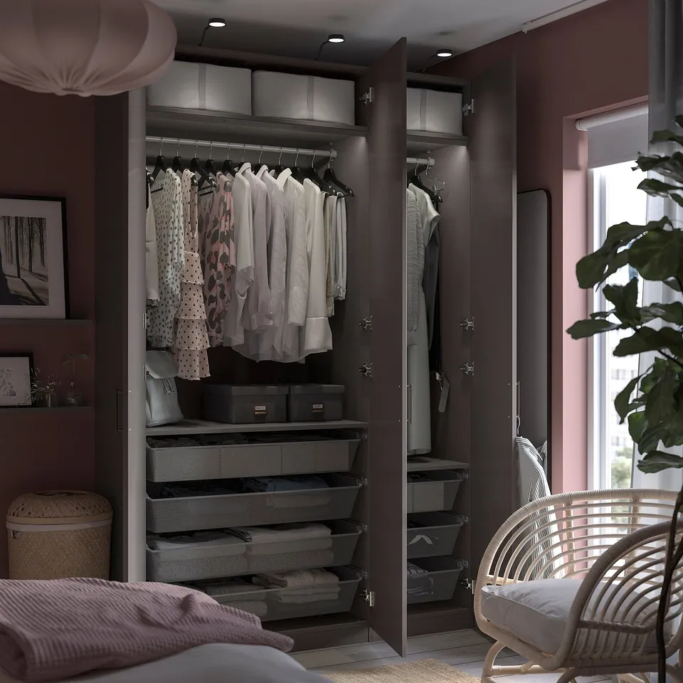 Modern dark closet with hanging shirts, folded clothes, mesh baskets, and wicker chair.