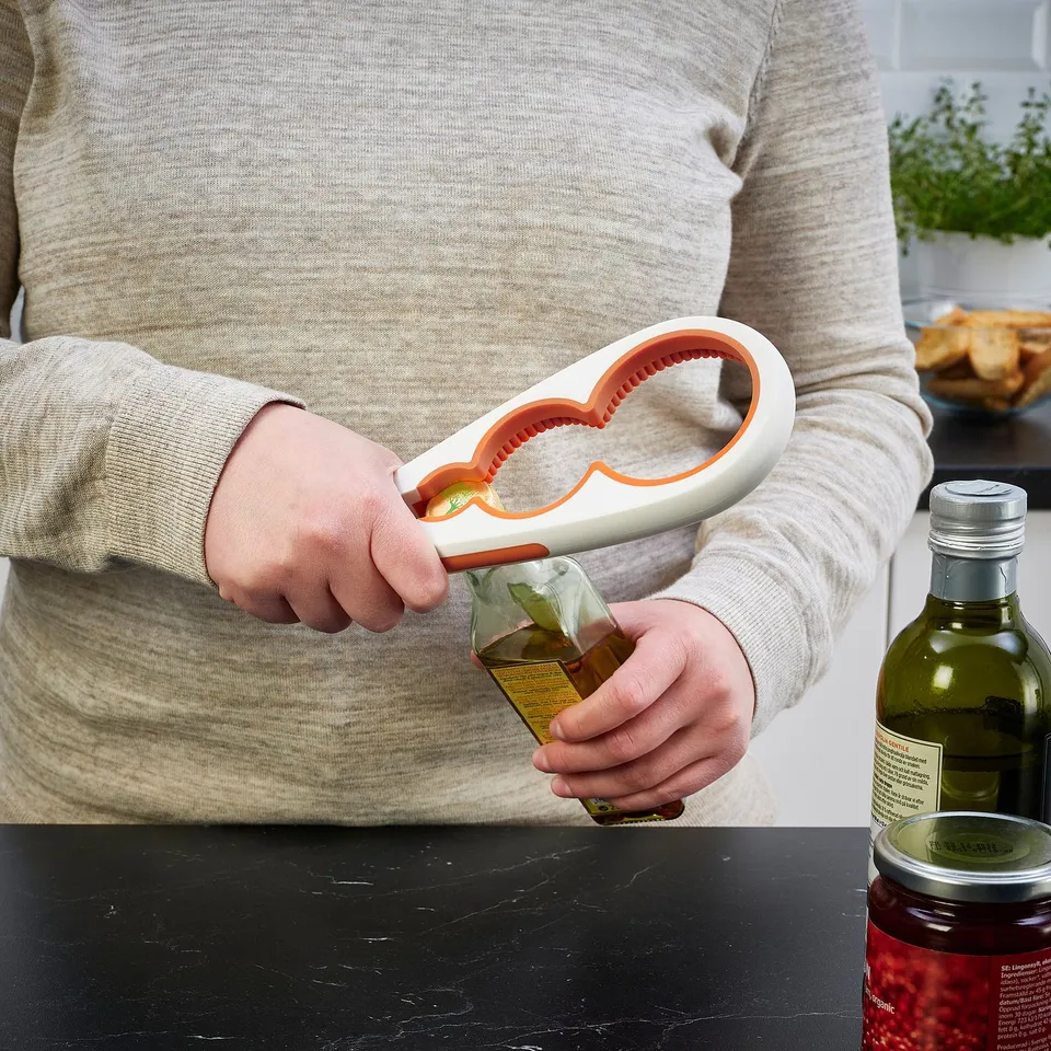 Person opens jar using UPPFYLLD jar opener, ensuring grip with silicone handle and inner surface.