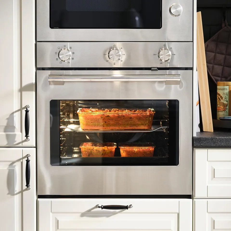 Stainless steel oven with glass door showing two glass food containers with cooked food inside.