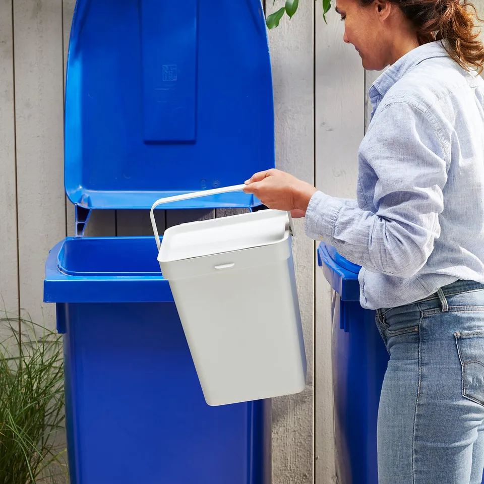 A person disposal wastes into blue HÅLLBAR bins, promoting recycling.
