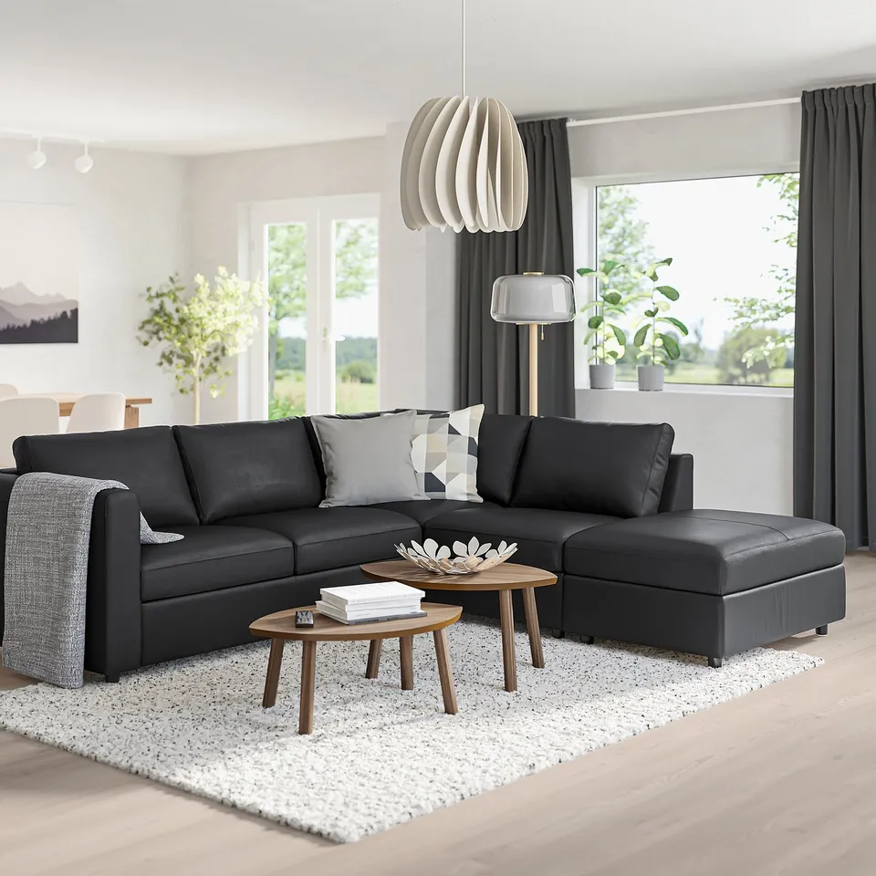 Modern living room with large black VIMLE sectional sofa, wood coffee tables, grey curtains, and large window.