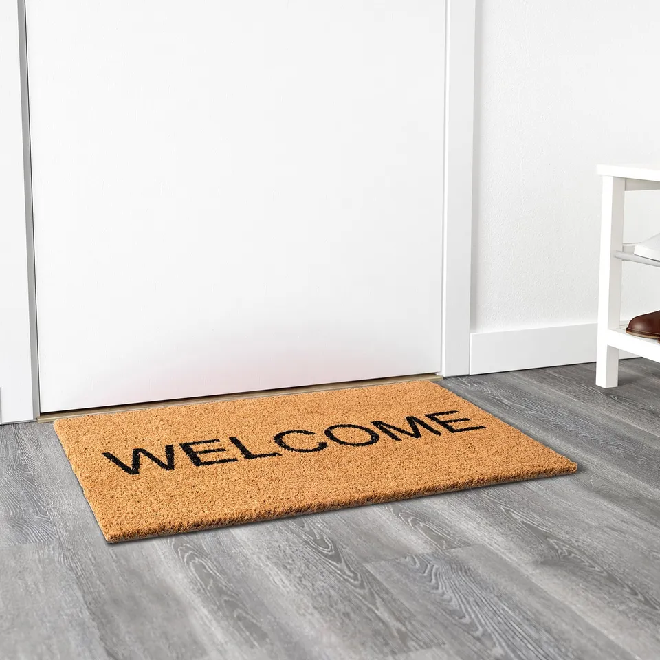 Doormat with welcome text, made of durable coconut fibres, placed at entrance, keeps floors clean.
