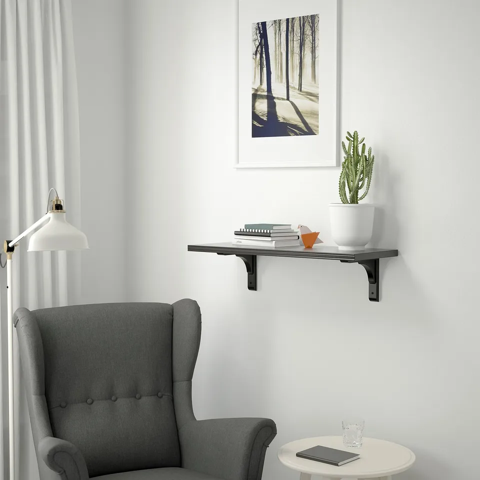 Modern living room with wingback chair, bookshelf, plant, and lamp.