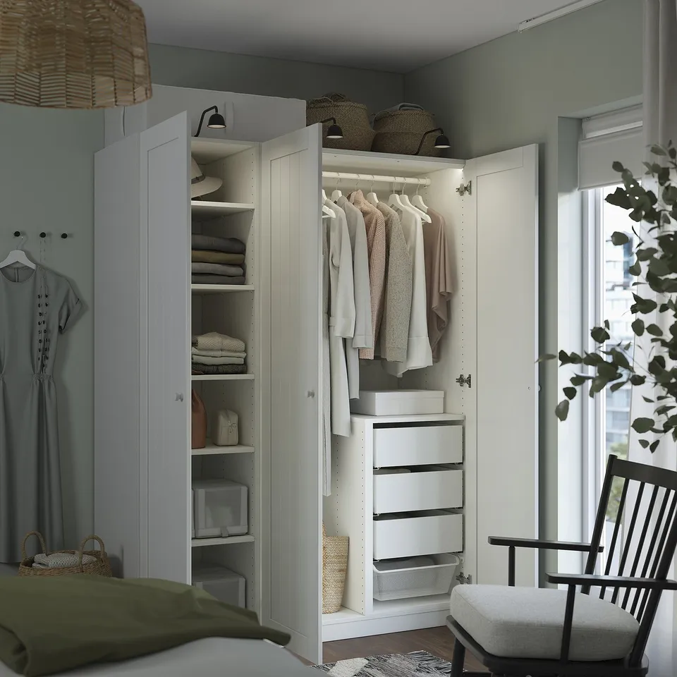 Open white wardrobe with clothes and baskets inside, based on PAX system.