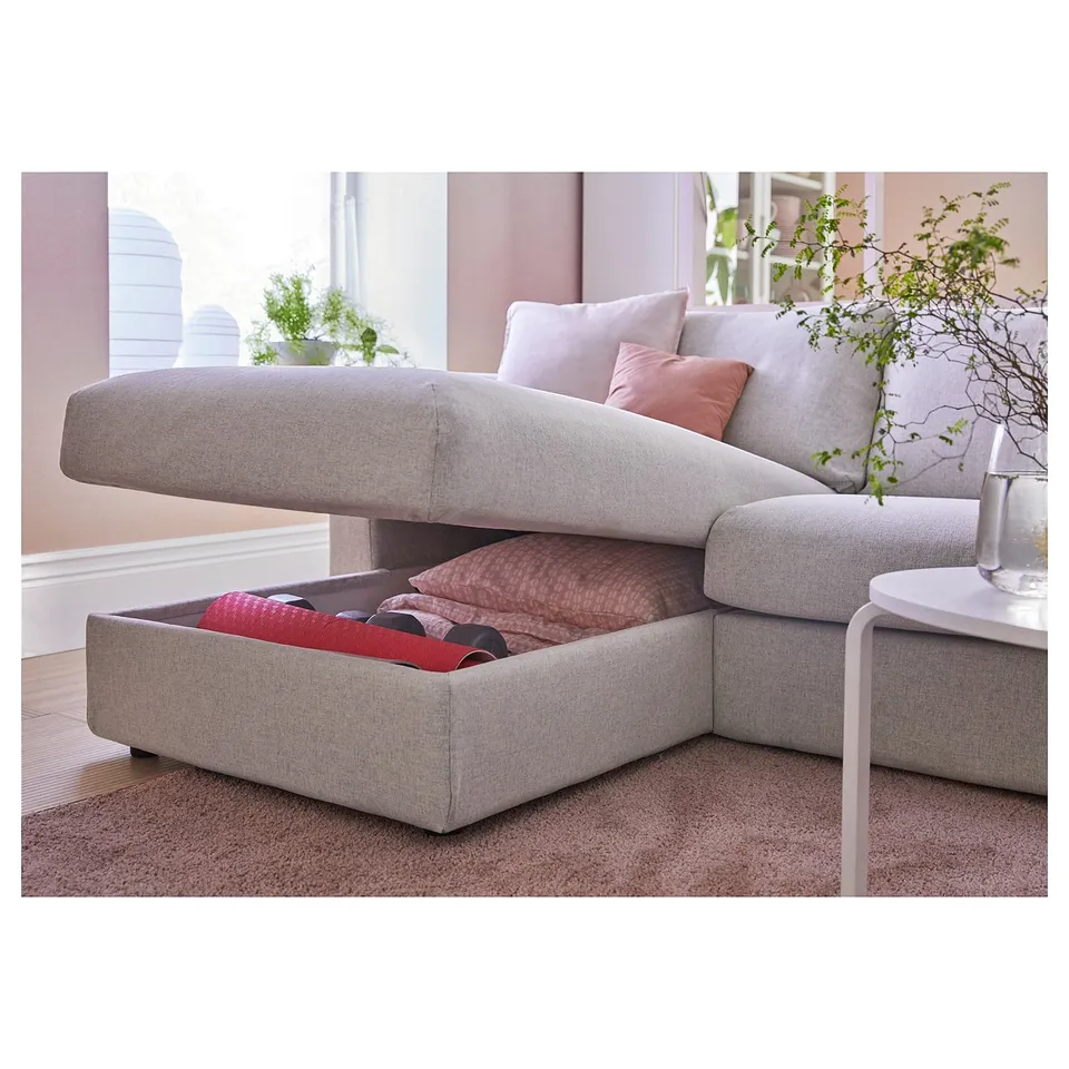Modern grey sofa with storage, pink pillows, and plants.