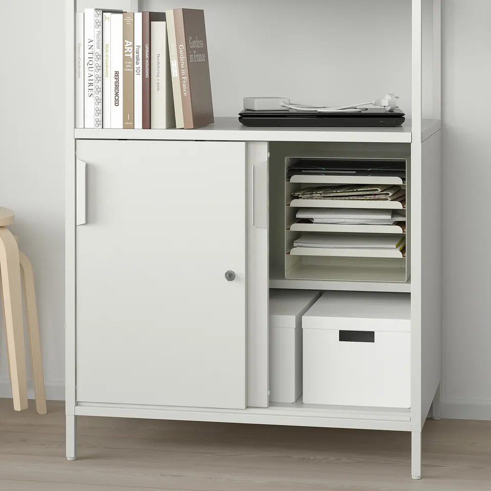 Double-sided storage cabinet, one side open with binders, one closed. Organised storage.