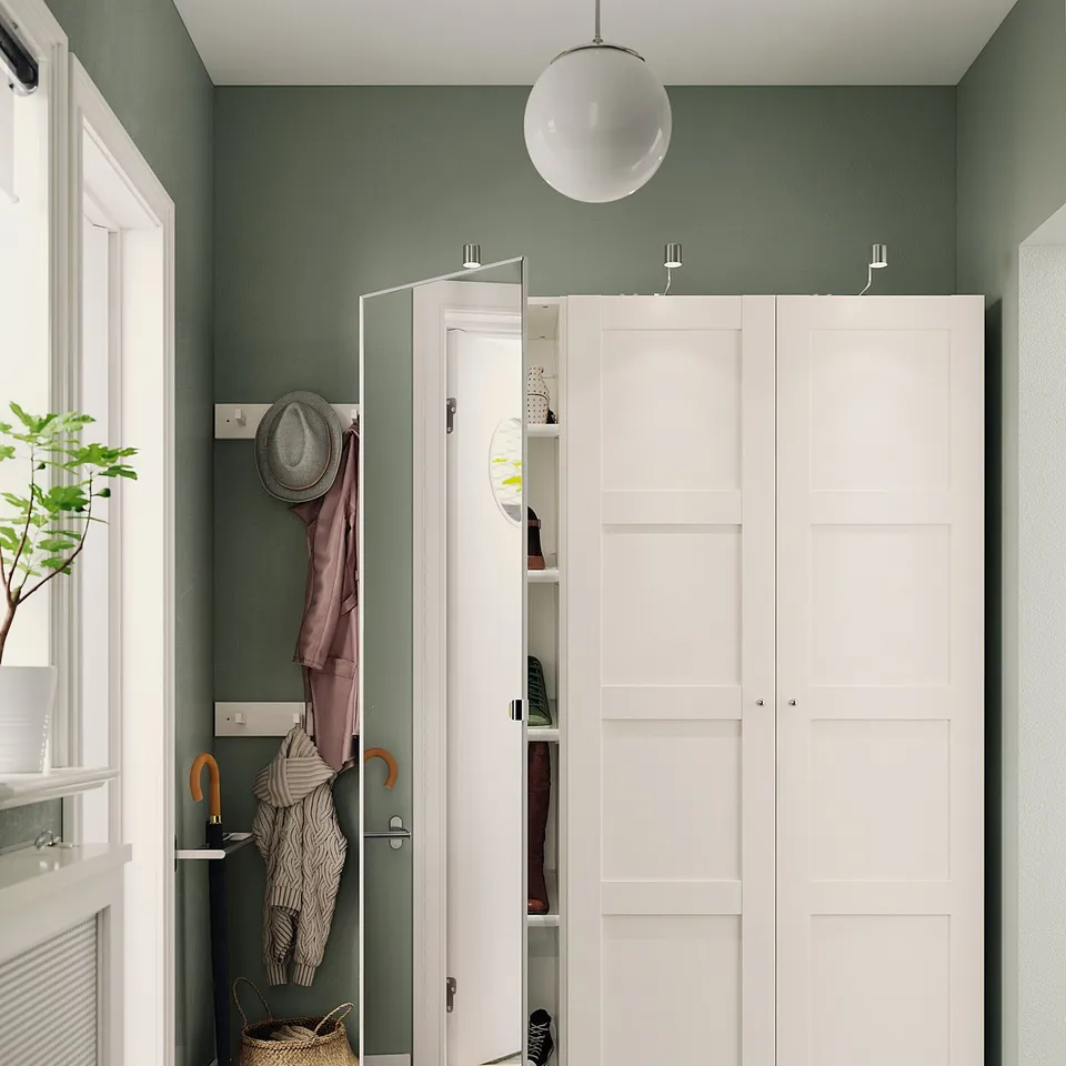 Modern entrance with white BERGSBO door and closet against sage green walls.