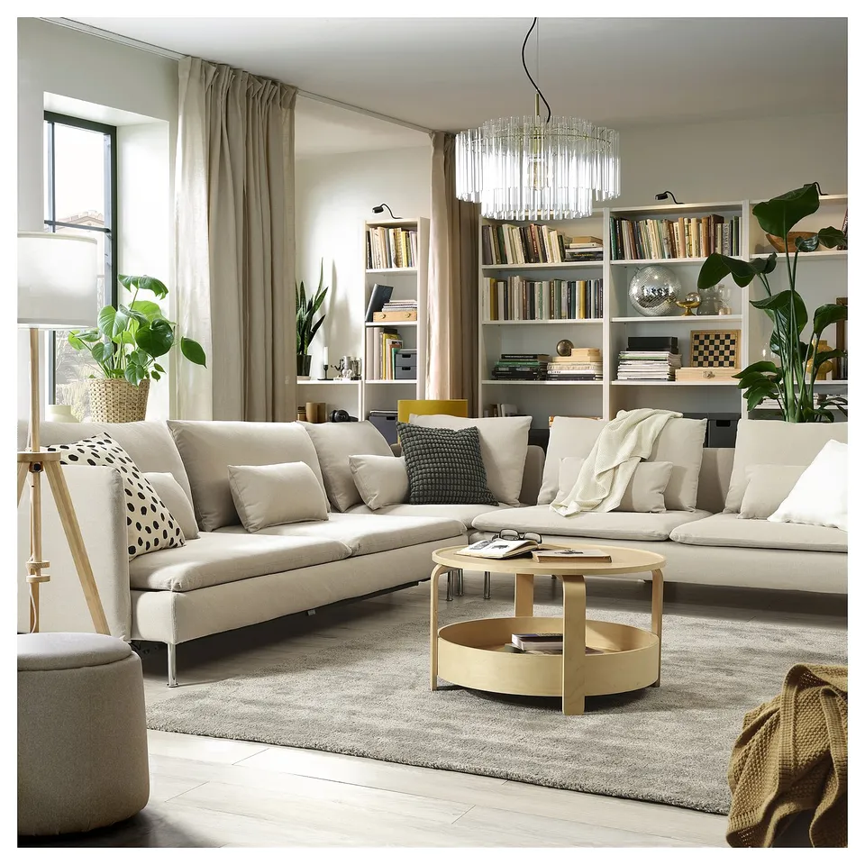 Modern living room with beige SÖDERHAMN sofa bed, white coffee table, bookshelf, and chandelier.
