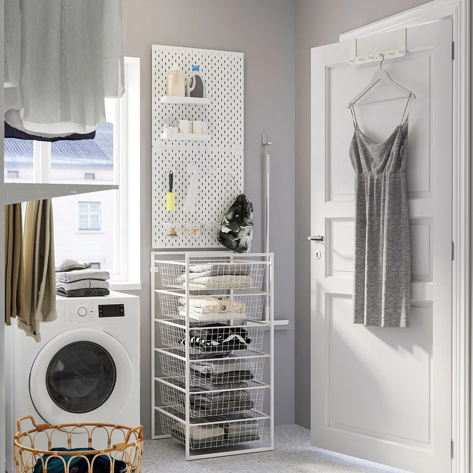 Laundry room with JONAXEL white storage, washing machine, hanging fabrics, and wicker basket.