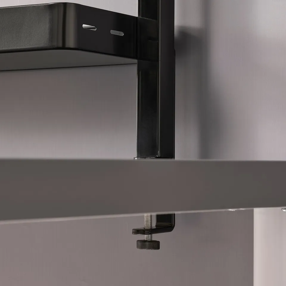 Black shelf unit with metal brackets, mounted on a table. Adjustable screws visible for stability.