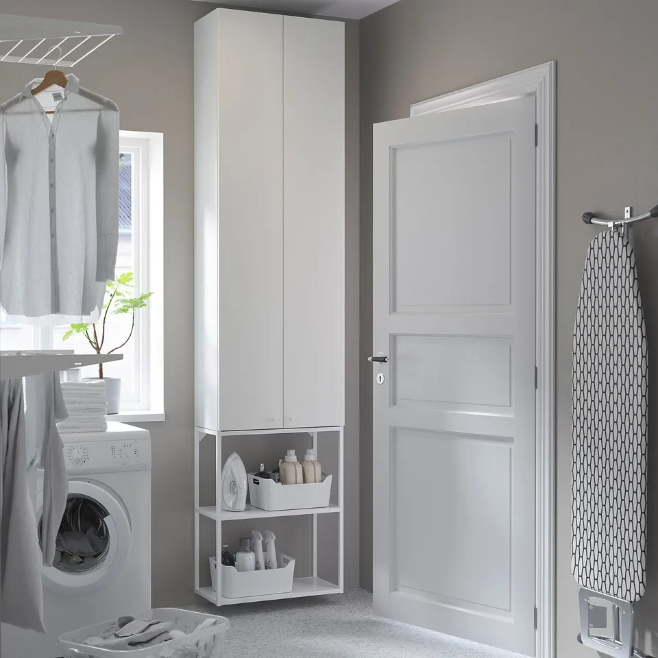 Modern laundry setup with white ENHET cabinet, washing machine, hanging clothes, and door.