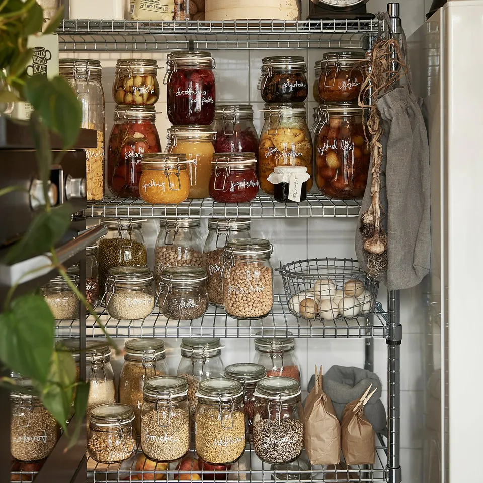 Shelves display KORKEN jars storing pickles, jams, grains. Jars airtight seals preserve food freshness.