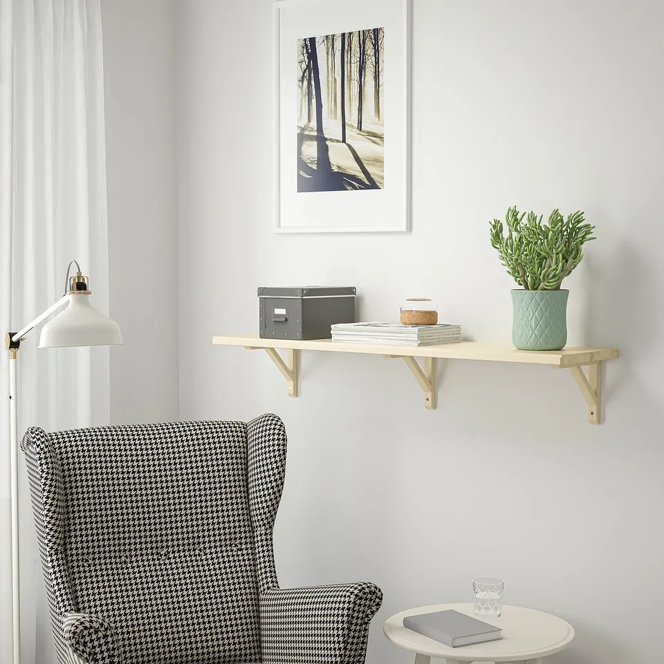 Cosy reading nook with TRANHULT shelf, armchair, table, plant, books, picture.