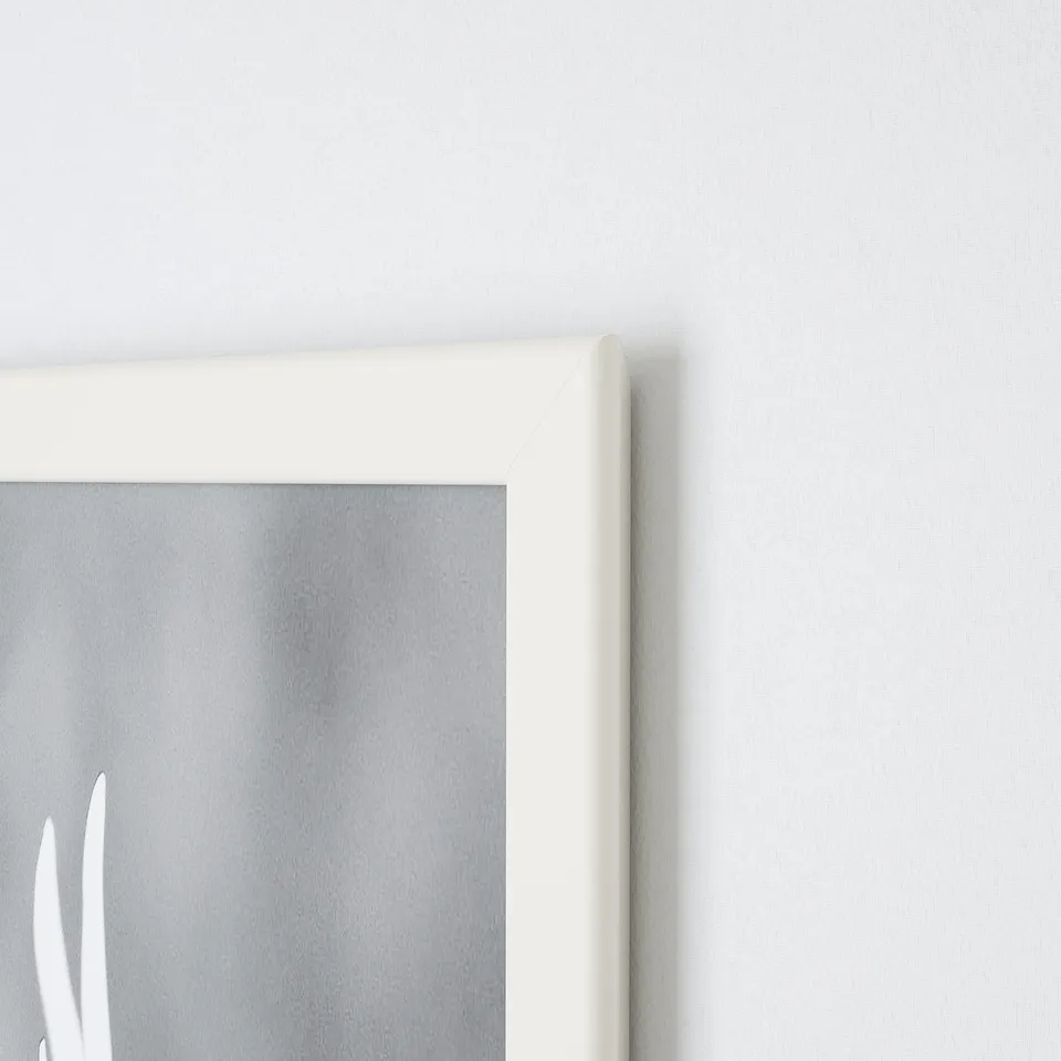 A close-up of a white picture frames clean edge against a light wall, showing its crisp lines and neat design.