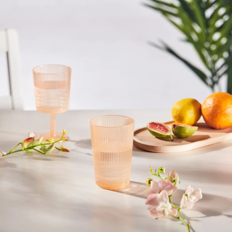 Plastic cups with fruit and flowers on table.
