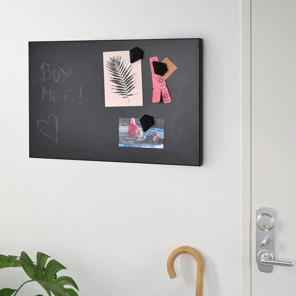 Black magnetic chalkboard on wall holds paper, photos, and notes. Used for reminders and decorations.