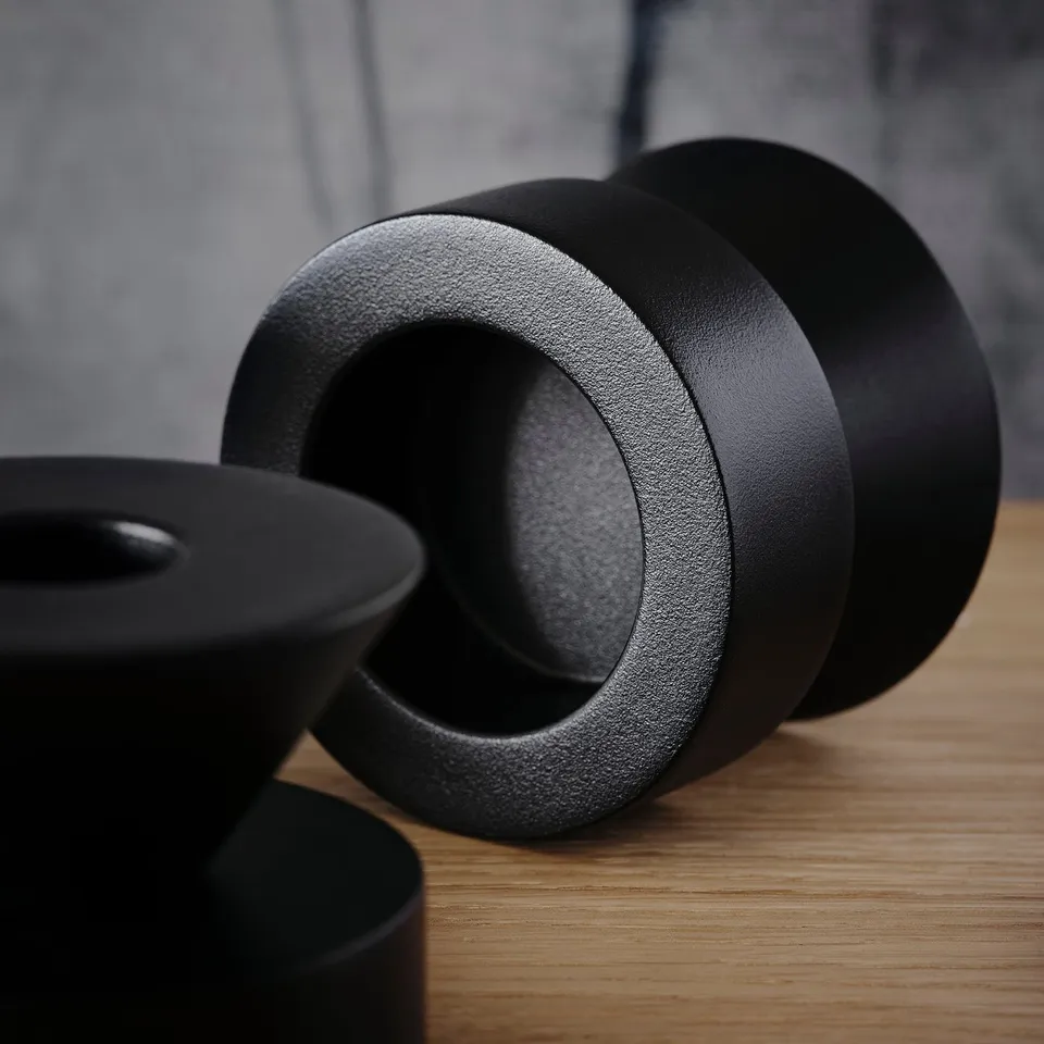 Black metal candlesticks on a wooden table. Sturdy and heavy, showcasing quality craftsmanship.