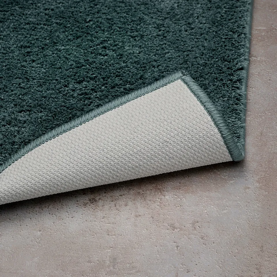 Green bath mat with white backing, showing soft texture and latex grip.
