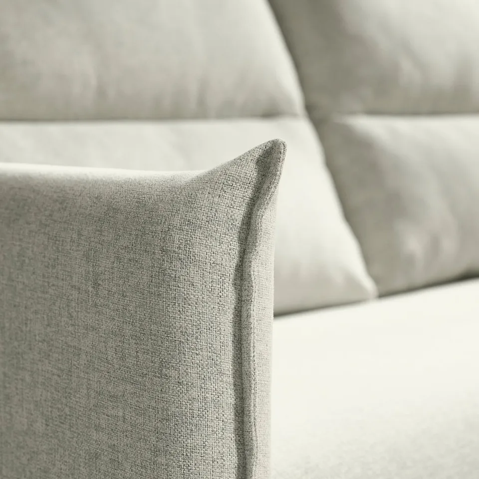 Close-up of plush, textured grey sofa cushion, showcasing soft, inviting upholstery with neat stitching.