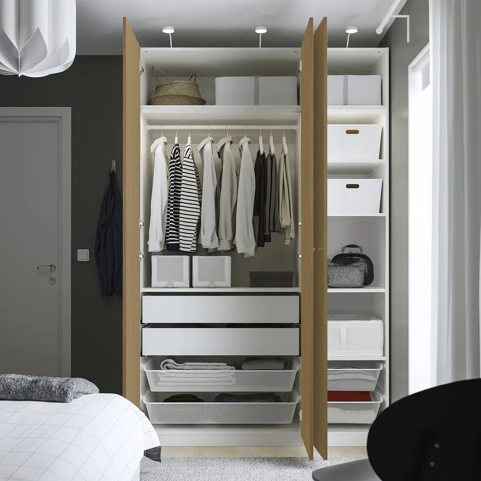Open wardrobe displaying folded clothes, shelves, drawers, and storage bins, showcasing organised bedroom storage.