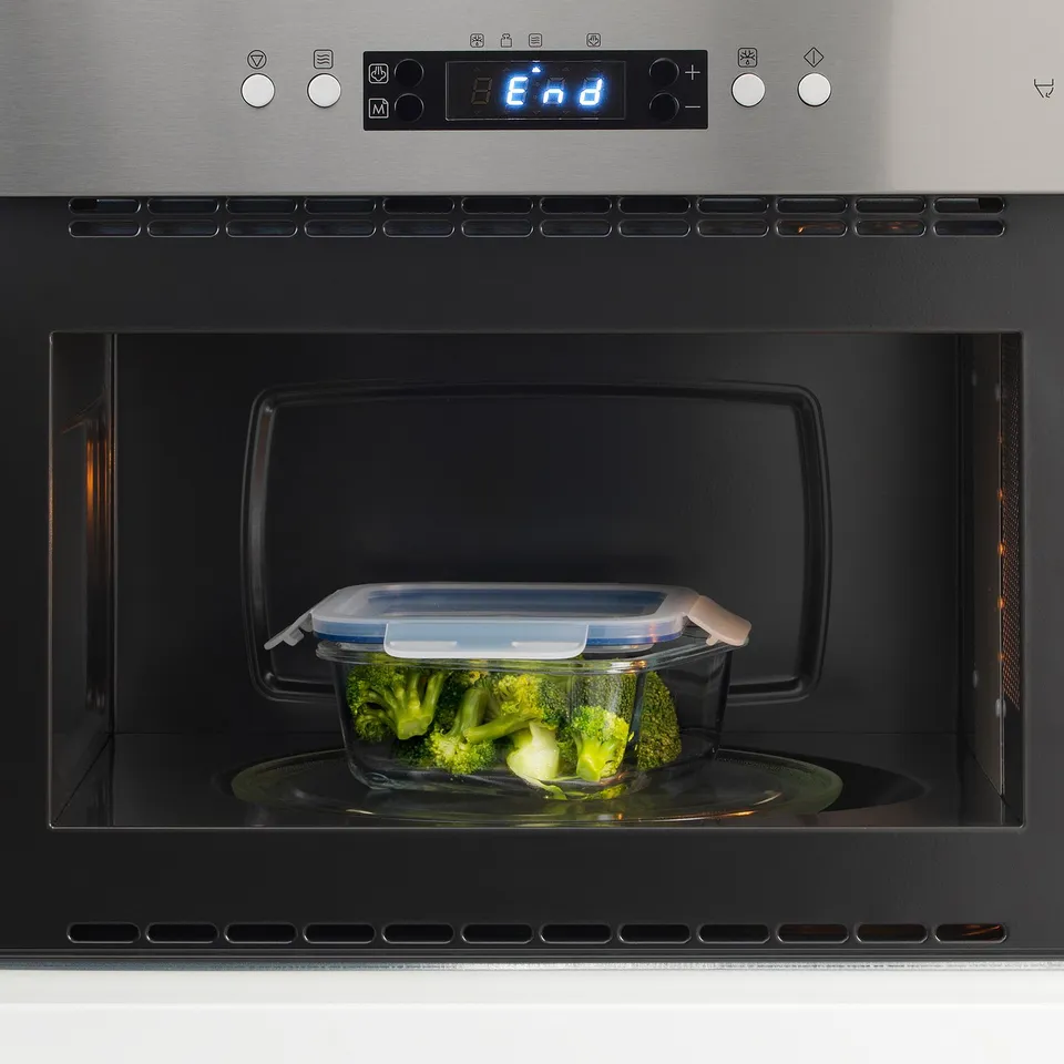 Microwave with glass dish containing broccoli, displaying end status.