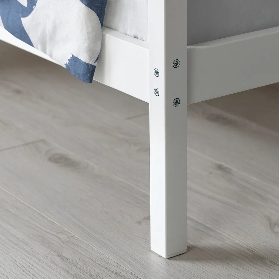 A close-up of a sturdy, white metal bed frame leg, featuring clean lines and secure screws, indicating high-quality construction.