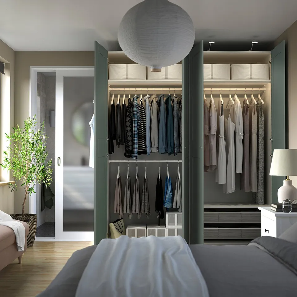 Modern wardrobe with sliding doors, organised clothes, storage boxes, & hanging garments.