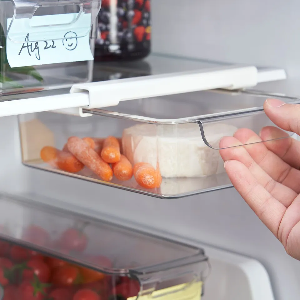 Colourful veggies and cheese stored in a clear fridge organiser, pulled out from under a shelf.