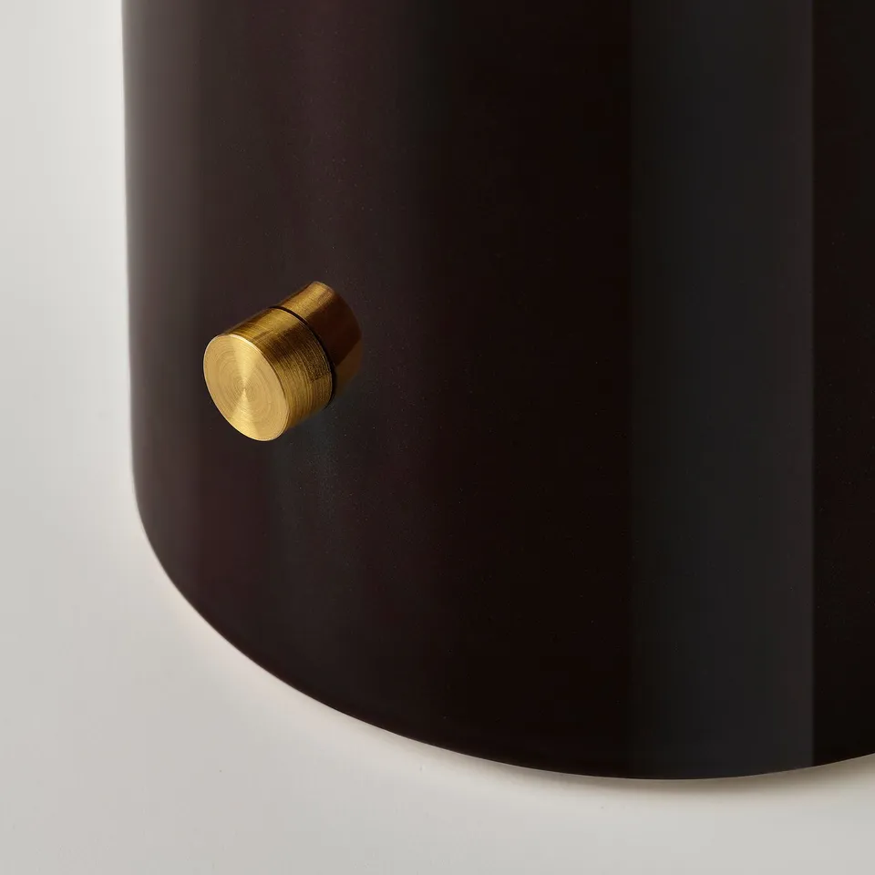 Cylindrical black lamp base with gold metal knob. Elegant design with smooth finish.