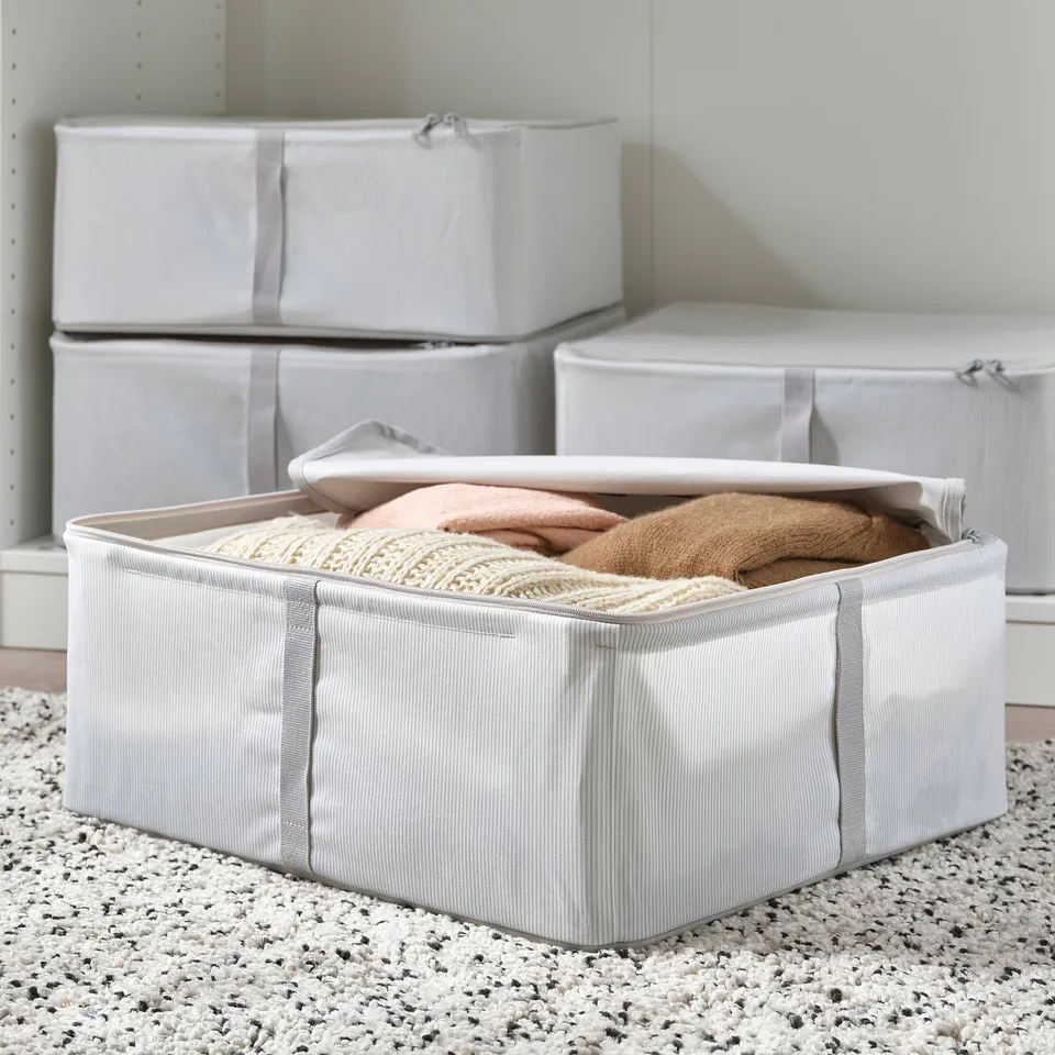 Storage boxes filled with folded clothes, stacked neatly. Ideal for organising and protecting items from dust. Part of the HEMMAFIXARE series.