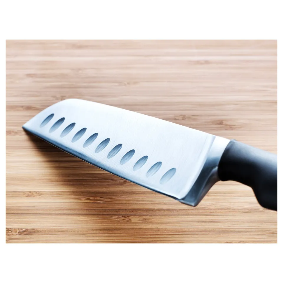 Silver knife with black handle resting on wooden surface, featuring blade indentations for better grip.