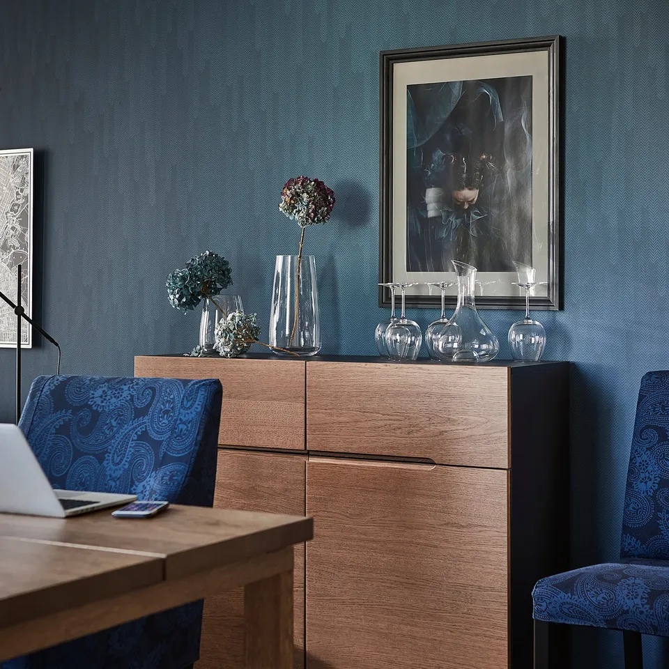 Modern dining room with KLACKENÄS oak veneer sideboard, blue patterned chairs, and wall art.