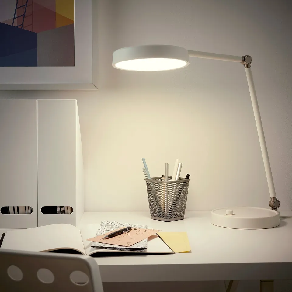 Modern ORSALA desk lamp in white, evenly illuminating workspace with book, notes, and pen holder; minimalist design.