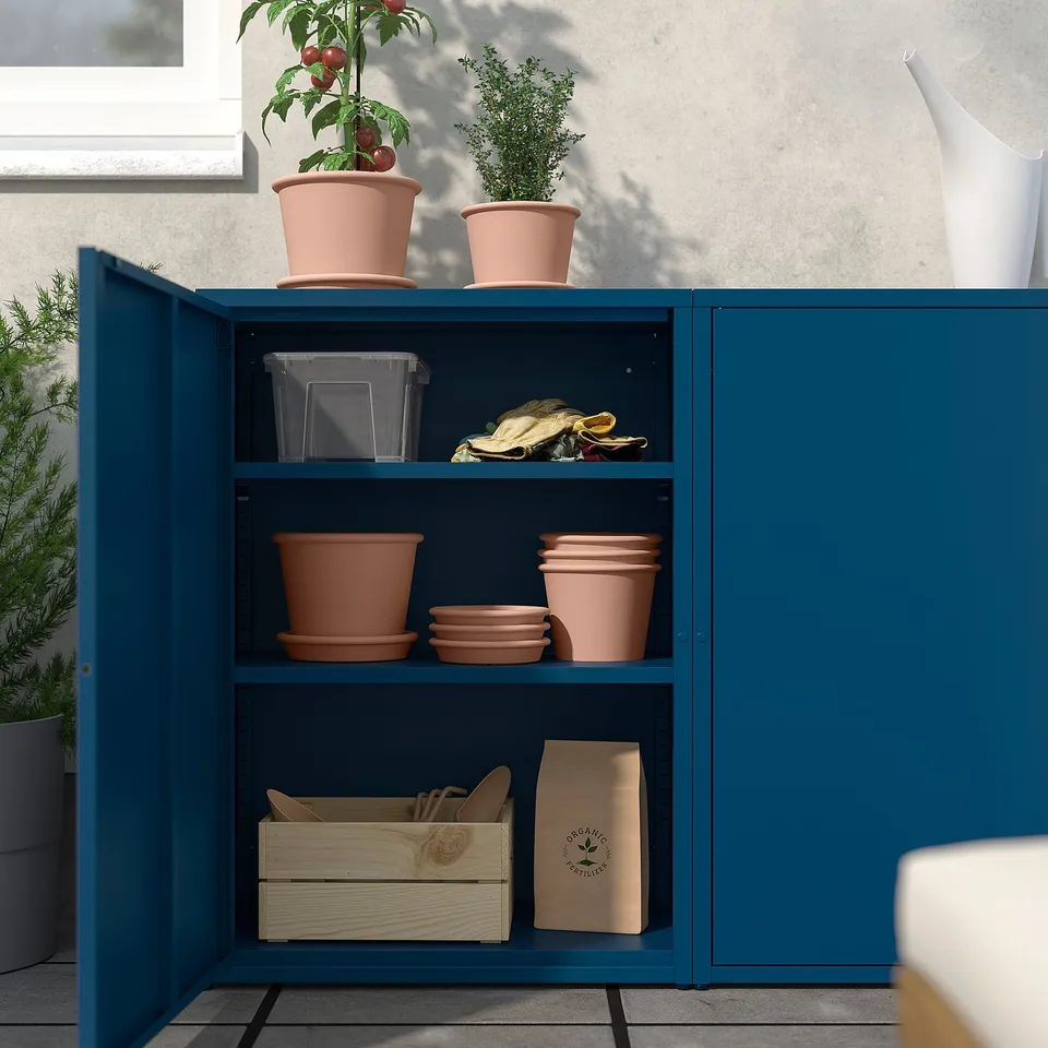 Blue SUNDSÖ cabinet with terracotta pots, plants, wooden and paper boxes on shelves.