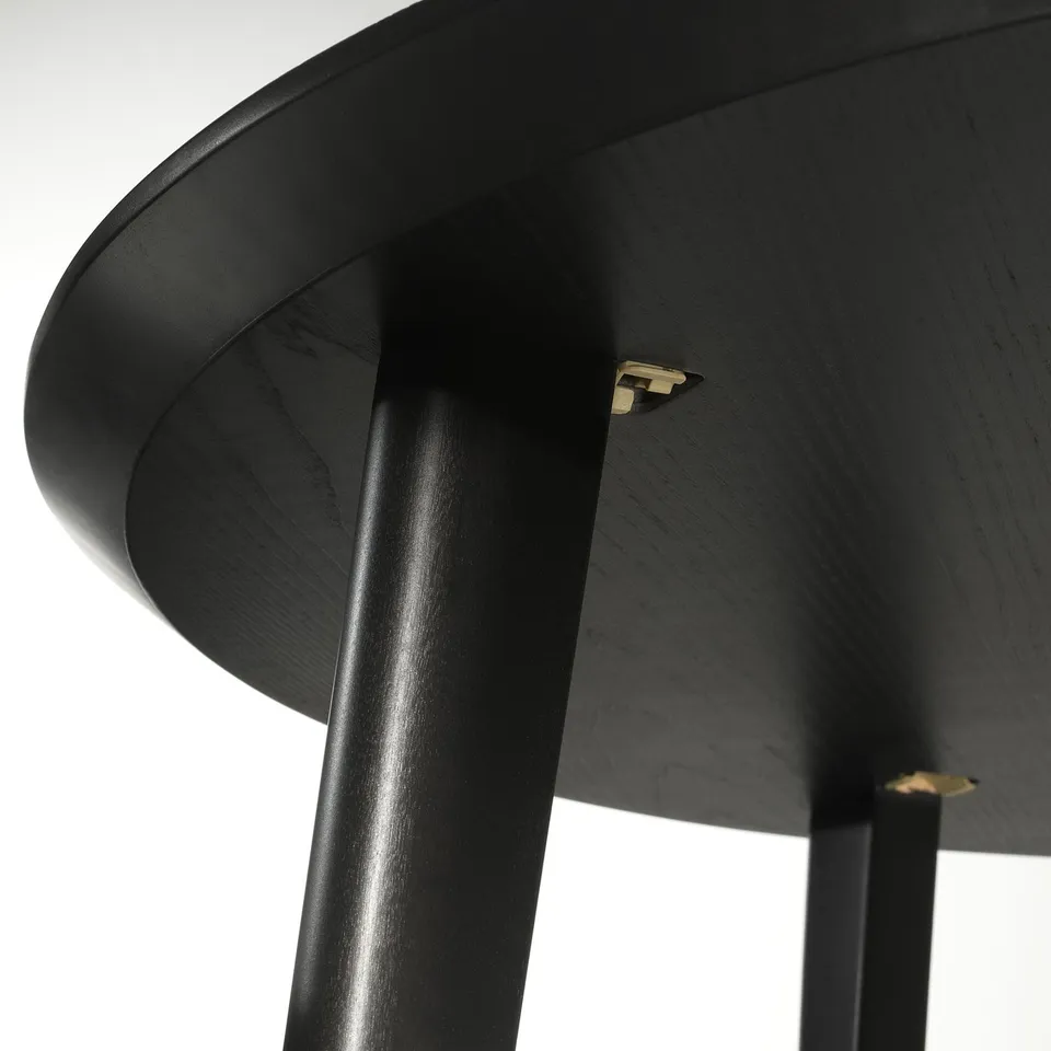 Black wooden table close-up, showing smooth, curved edges and sleek, dark finish.